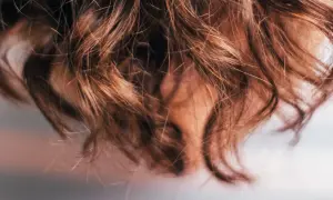 Närbild på brunt, vågigt hår som ser ut att ha fått en behandling med hair botox för extra glans och mjukhet.