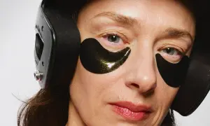Närbild på en kvinna med mogen hud, bärandes svarta ögonlappar och hörlurar.