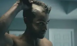 Man rakar huvudet med maskin, en del av håret är redan borta.