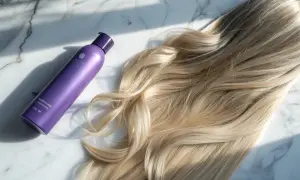 Lila flaska bredvid blont hår. Perfekt för att få bort blått hår och ge glans.