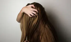 En hand drar genom tjockt, brunt hår. Kanske är det dags för lite biotin för håret för att hålla det friskt och starkt.