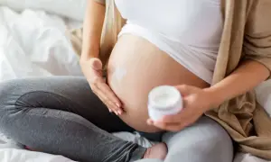 En gravid kvinna smörjer in sin mage med kräm. En ansiktsmask gravid kan vara en del av hudvårdsrutinen.