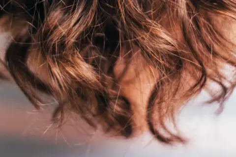 Närbild på brunt, vågigt hår som ser ut att ha fått en behandling med hair botox för extra glans och mjukhet.