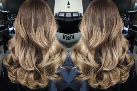 Vackert balayage hår med mjuka vågor och gyllene toner.