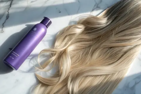 Lila flaska bredvid blont hår. Perfekt för att få bort blått hår och ge glans.
