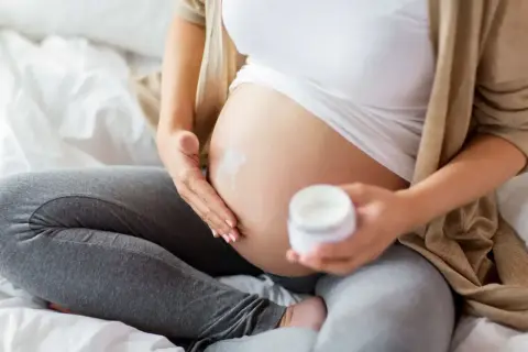 En gravid kvinna smörjer in sin mage med kräm. En ansiktsmask gravid kan vara en del av hudvårdsrutinen.