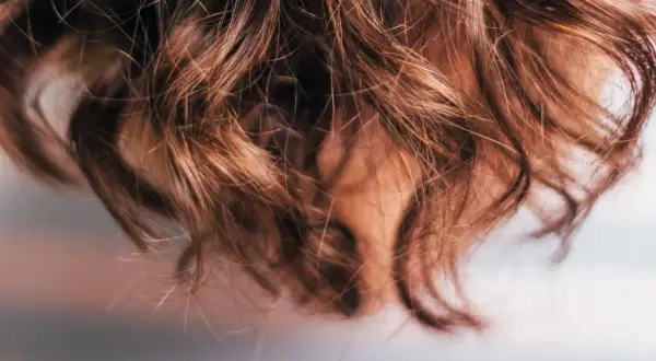 Närbild på brunt, vågigt hår som ser ut att ha fått en behandling med hair botox för extra glans och mjukhet.