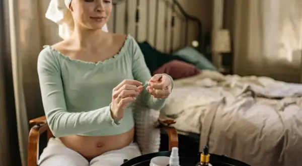 Gravid kvinna med handduk på huvudet tar hand om sin hud med produkter, kanske med niacinamid för en säker graviditet.