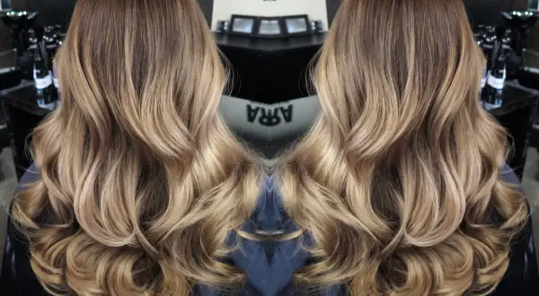 Vackert balayage hår med mjuka vågor och gyllene toner.