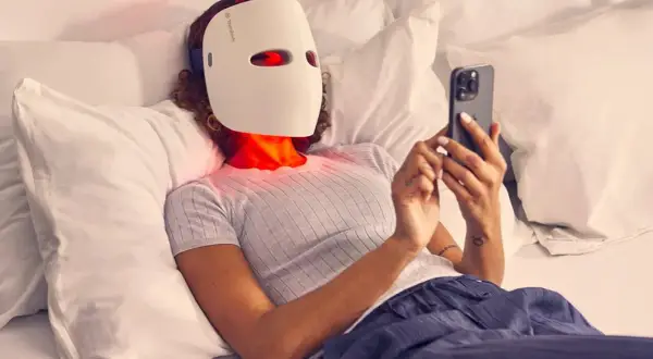 Person med led mask ansikte ligger i sängen och scrollar på mobilen.
