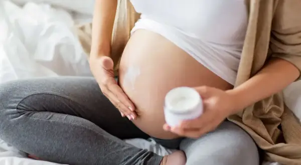 En gravid kvinna smörjer in sin mage med kräm. En ansiktsmask gravid kan vara en del av hudvårdsrutinen.