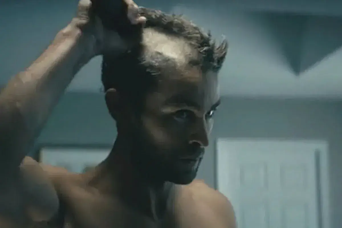 Man rakar huvudet med maskin, en del av håret är redan borta.