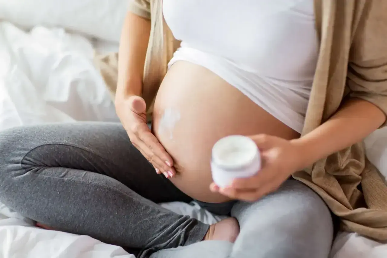 En gravid kvinna smörjer in sin mage med kräm. En ansiktsmask gravid kan vara en del av hudvårdsrutinen.