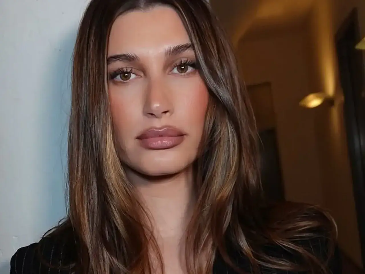 En kvinna med slingat brunt hår och en mjuk makeup-look.