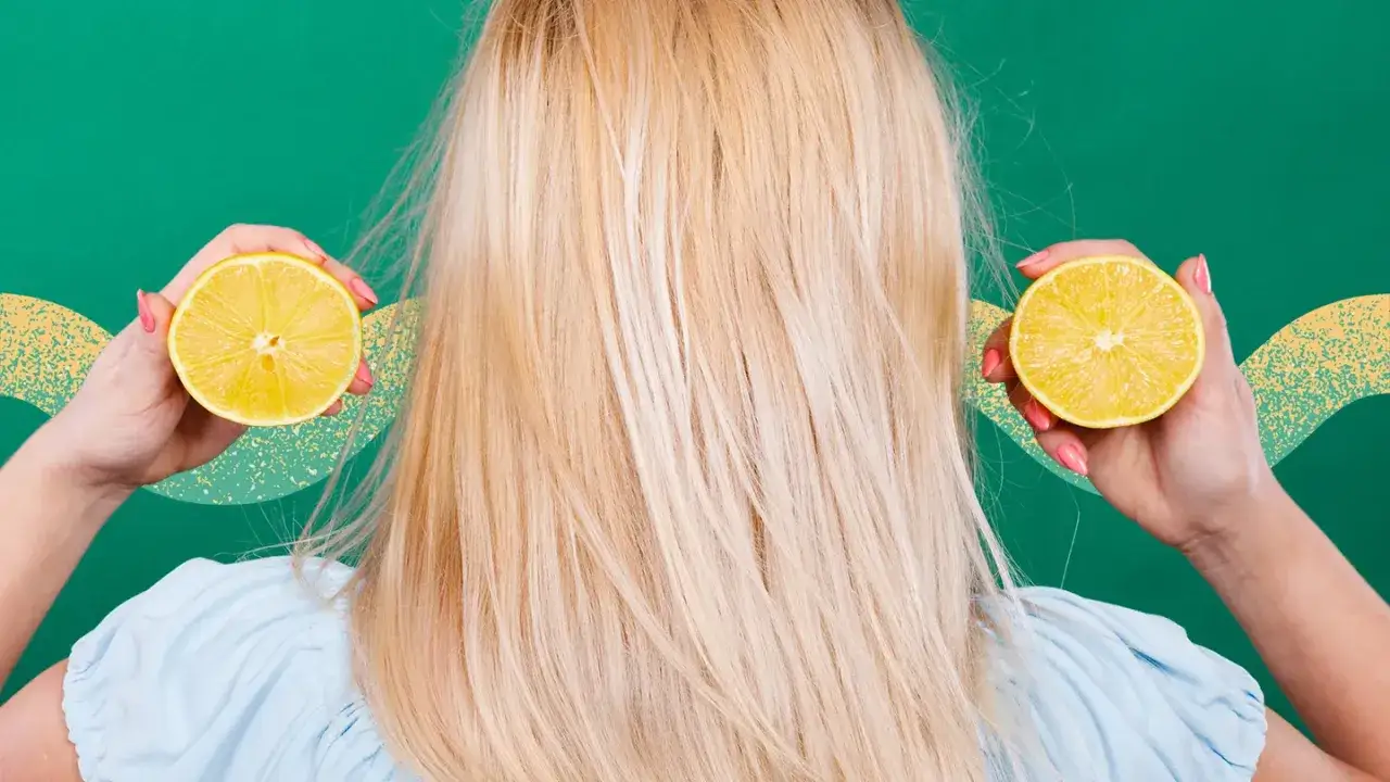 Kvinnan h&aring;ller upp citronhalvor vid sitt blonda h&aring;r, som om hon vill bleka h&aring;ret med citron och bakpulver f&ouml;r en naturlig glans.