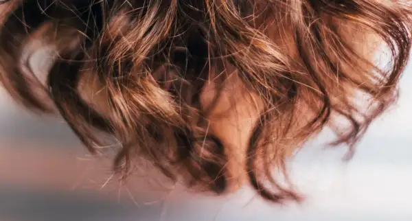 Närbild på brunt, vågigt hår som ser ut att ha fått en behandling med hair botox för extra glans och mjukhet.