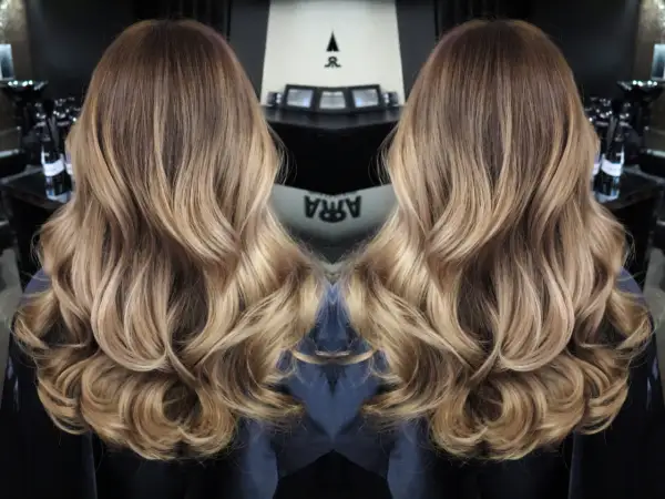 Vackert balayage hår med mjuka vågor och gyllene toner.